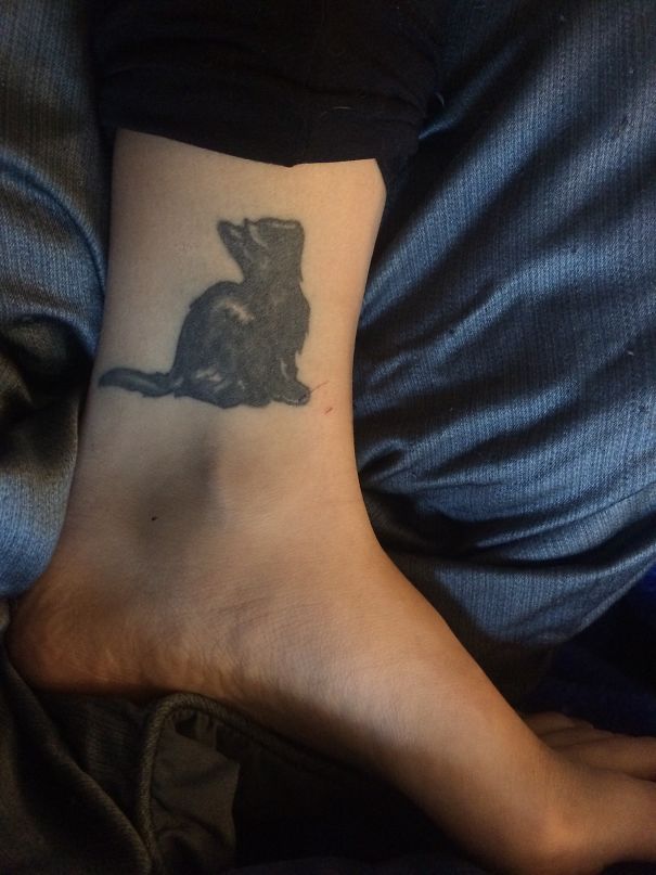 Black silhouette cat tattoo on an ankle, showcasing a simple design for cat person expression.