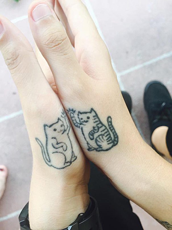 Minimalist cat tattoos on forearms of two people giving a high five, showcasing cat tattoo ideas for enthusiasts.