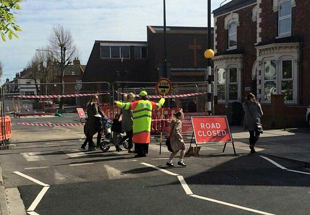 Picture of people walking on the road and sign that says road closed
