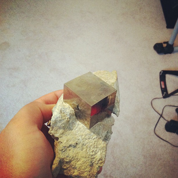 Hand holding a rock with a perfectly formed cube embedded, exemplifying perfect pics for a perfectionist's satisfaction.
