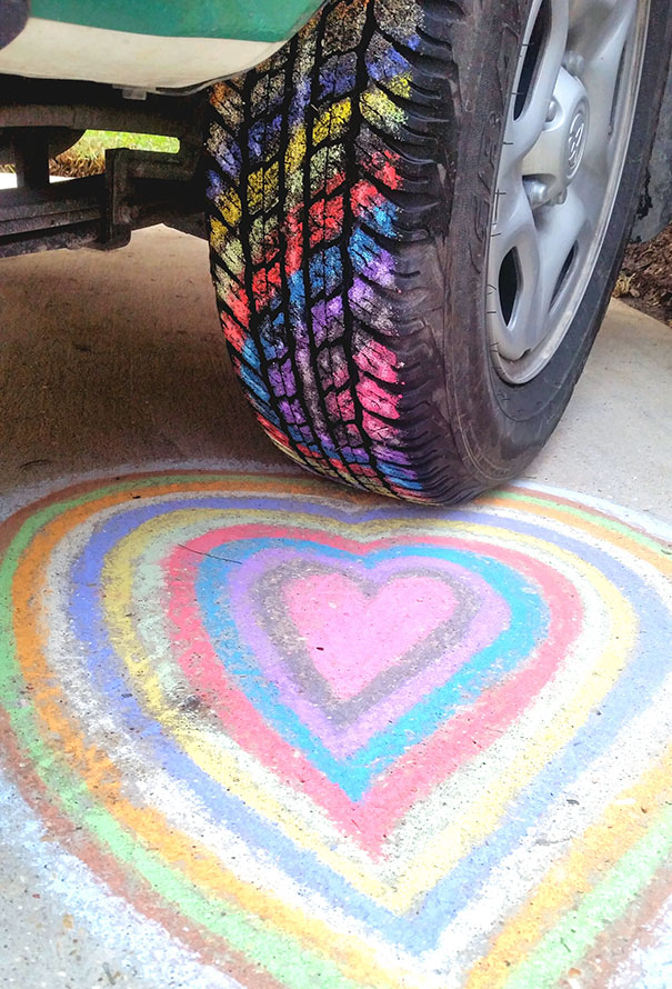 Colorful chalk heart pattern under a rainbow tire track, satisfying perfectionist's soul with symmetry and vibrant hues.