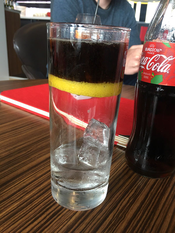 Layered glass with lemon, water, and cola, a perfect presentation for satisfying perfectionist's soul.