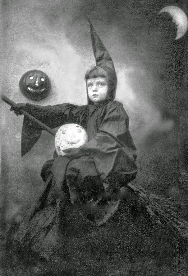 Child in a vintage Halloween costume dressed as a witch, holding a broomstick with spooky pumpkin props under a crescent moon.