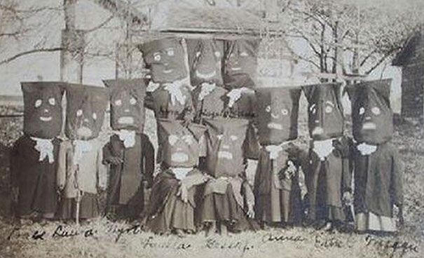Group of children wearing vintage Halloween costumes with paper bag masks featuring painted scary faces outdoors.