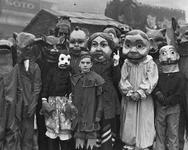 Group of people wearing vintage Halloween costumes with oversized masks, showcasing classic scary Halloween costume styles.