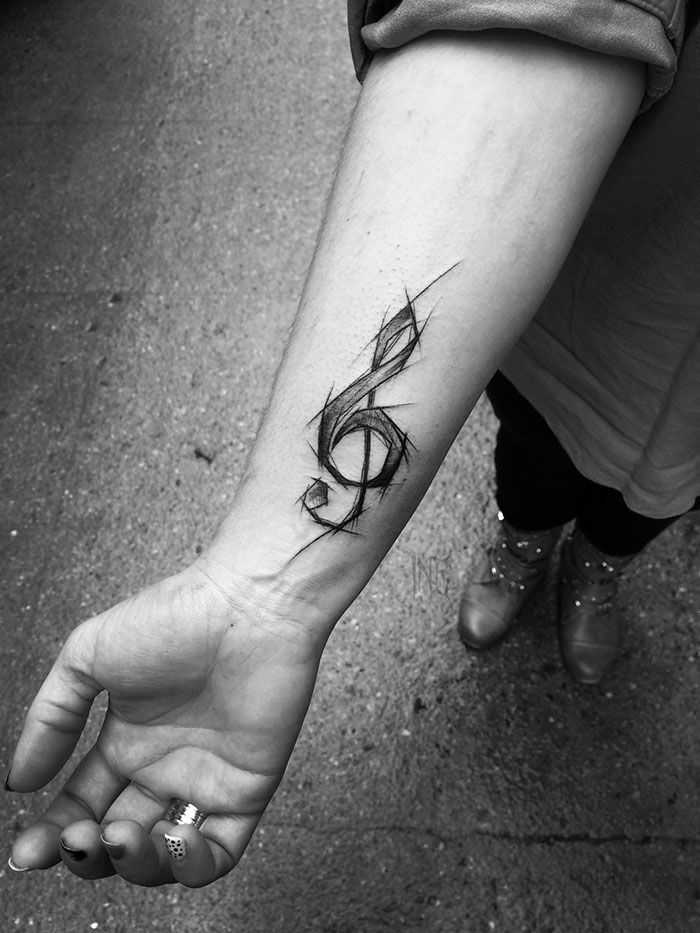 Sketch tattoo of a treble clef on forearm by Polish tattoo artist, showcasing the beauty of imperfection.