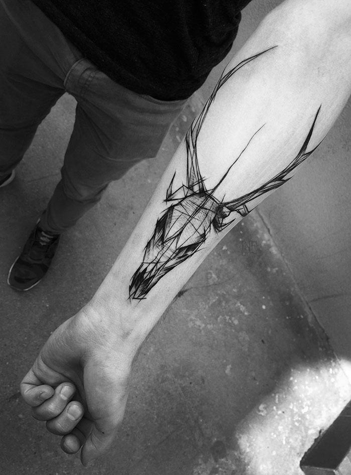 Sketch tattoo of a geometric deer skull on a person's forearm, showcasing the beauty of imperfection.