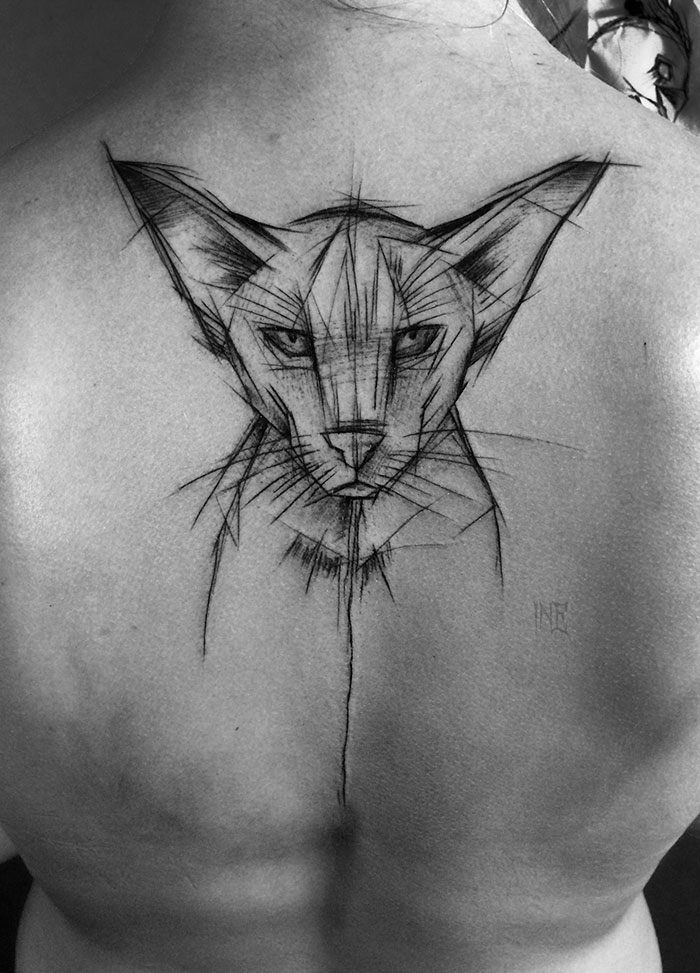 Sketch tattoo of a cat on a person's back by Polish tattoo artist, showcasing beauty in imperfection.