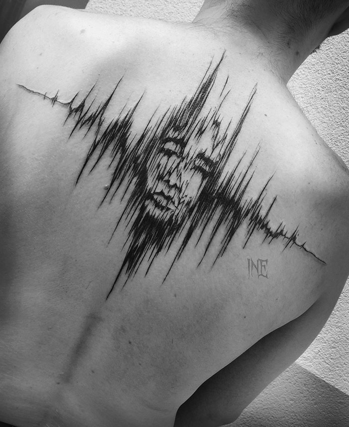 Sketch tattoo of a face on a person's back showcases the beauty of imperfection by a Polish tattoo artist.