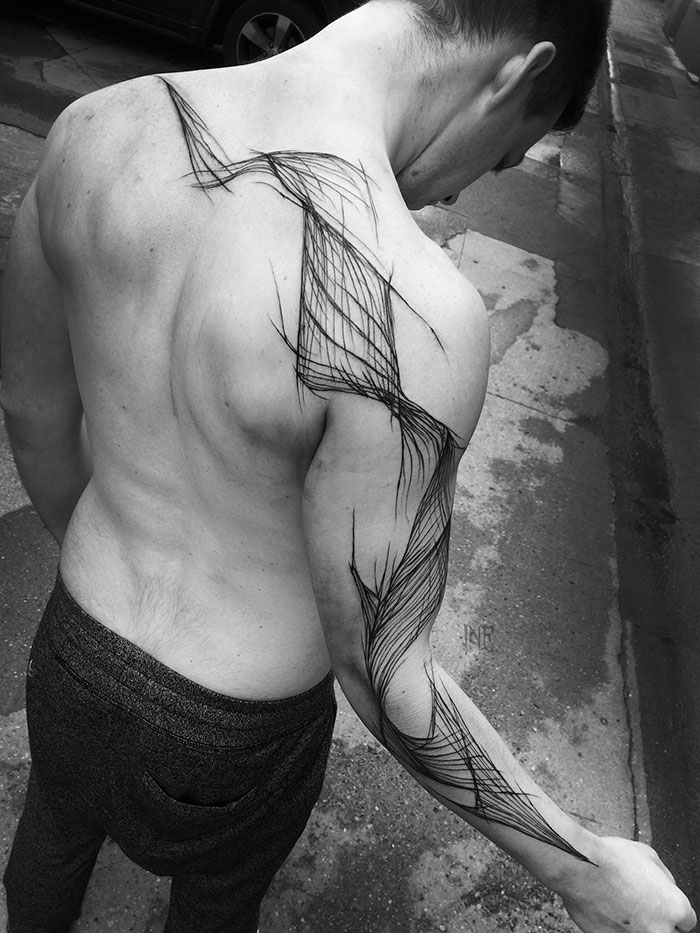 Man with intricate sketch tattoo design on back and arm, showcasing the beauty of imperfection by Polish tattoo artist.