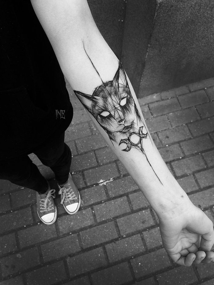 Sketch tattoo of a cat on a person's forearm by Polish tattoo artist, showcasing beauty in imperfection.