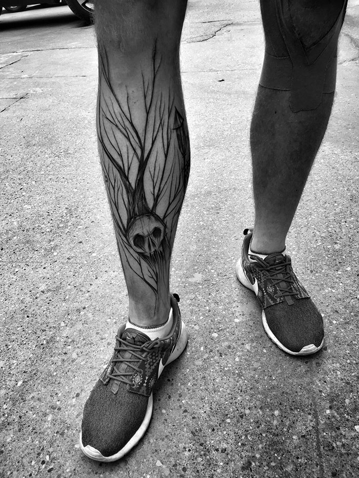 Sketch tattoo of branches and a skull on leg, showcasing beauty of imperfection.