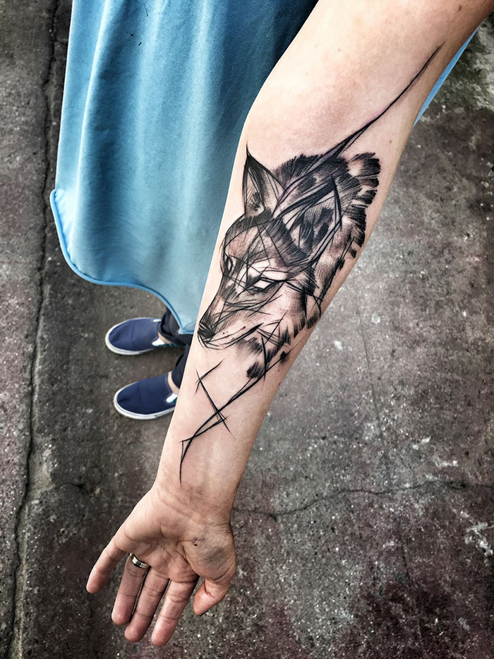 Sketch tattoo of a wolf on an arm by a Polish tattoo artist, showcasing beauty in imperfection.