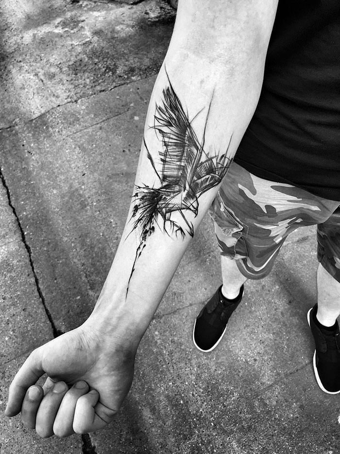 Sketch tattoo of a bird on a person's forearm, illustrating the beauty of imperfection.