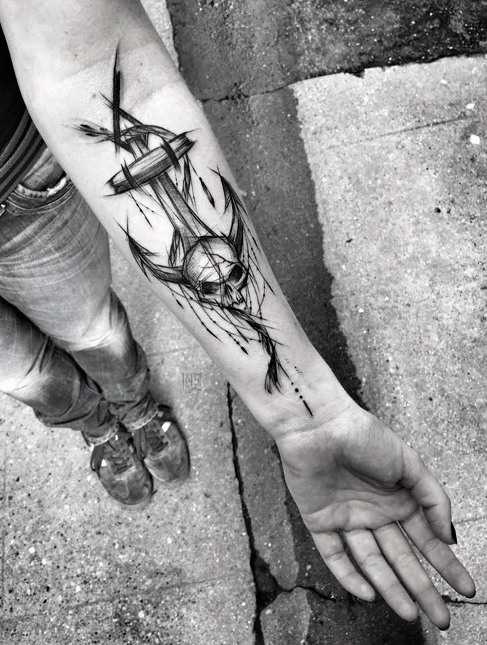 Sketch tattoo depicting a skull with abstract lines on a person's forearm, showcasing beauty in imperfection.