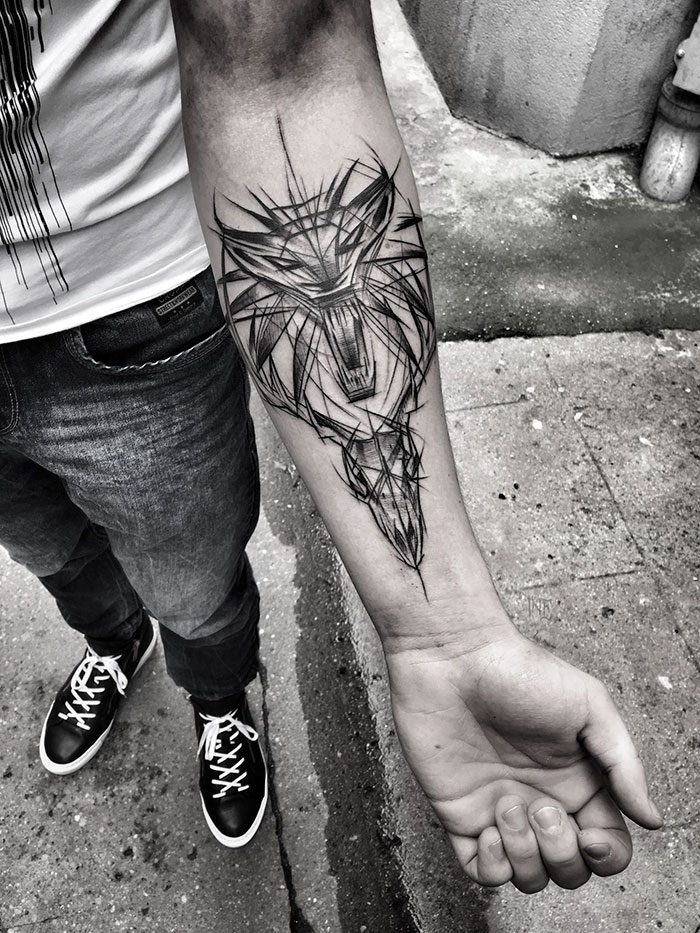 Sketch tattoo of a geometric wolf on a person's forearm, showcasing the beauty of imperfection by a Polish tattoo artist.