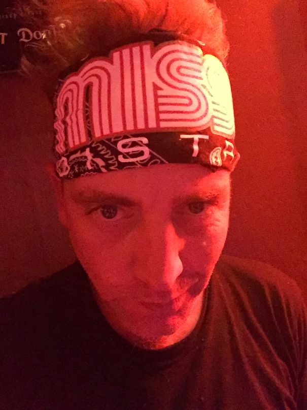 Man wearing a bandana in low red light, illustrating transformation in before-and-after pics showing stopping drinking effects.