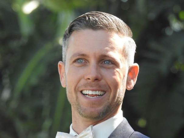 Smiling man in formal attire outdoors with clear skin and bright eyes, illustrating effects of stopping drinking.