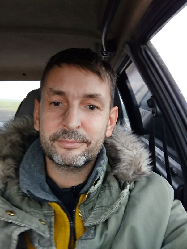 Man sitting in a car wearing a green fur-lined jacket, showing a calm and healthy look after stopping drinking.