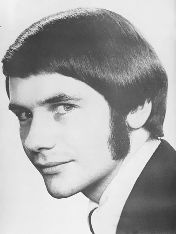 1960s men's hairstyle featuring sleek, side-parted hair with prominent sideburns, illustrating a classic romantic look.