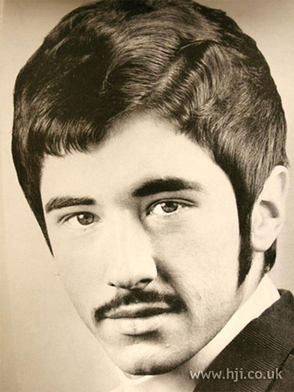 Portrait of a man showcasing romantic 1960s hairstyle with sideburns and mustache, emphasizing classic men's fashion.