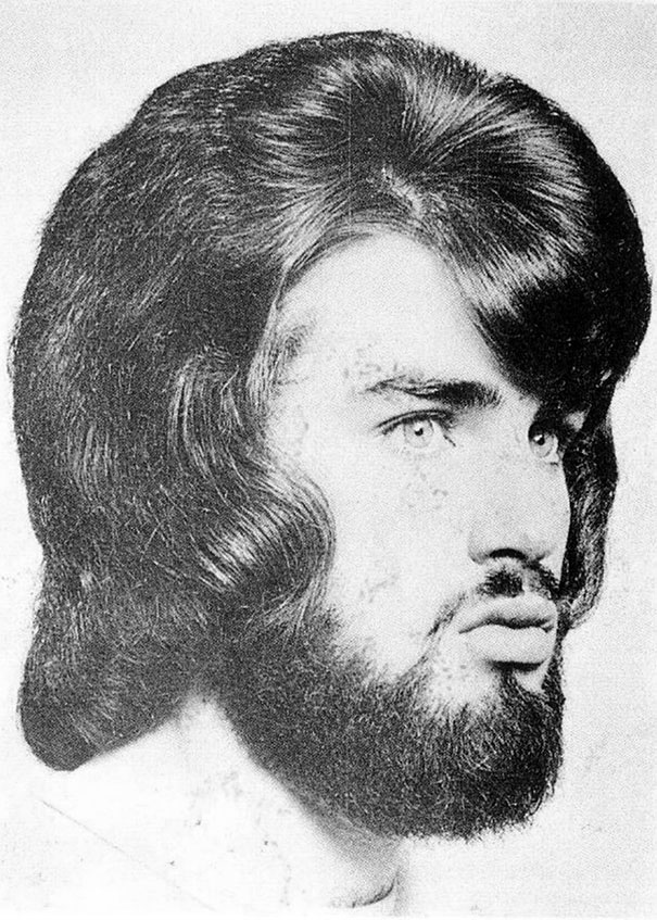 Man with voluminous 1960s hairstyle and beard in a vintage black and white photo.