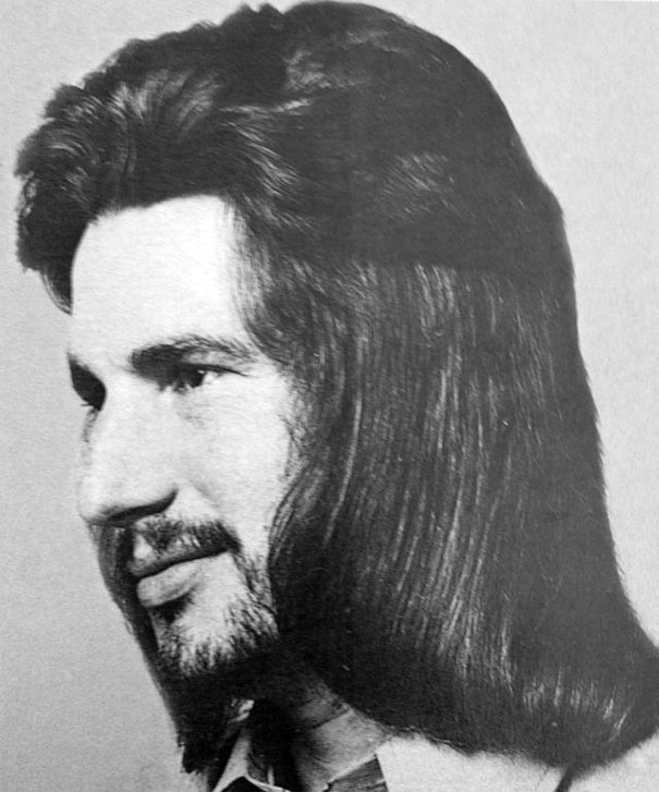 Man with long, romantic 1970s hairstyle, featuring smooth, flowing locks, showcasing iconic men's fashion of the era.