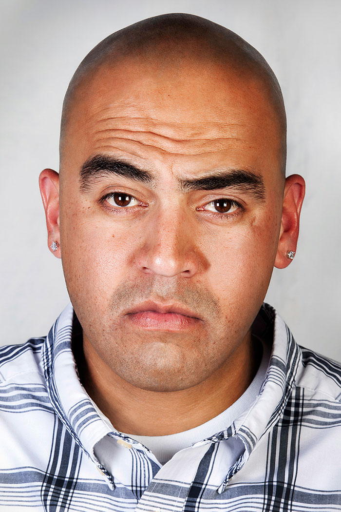 Ex-gang member with tattoos removed, wearing a striped shirt, looking directly at the camera. Ex-gang member with tattoos removed, wearing a striped shirt, looking directly at the camera.