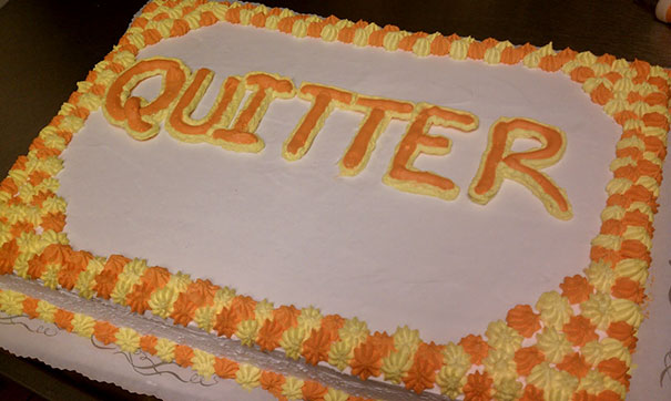 Farewell cake with "Quitter" written in orange icing, framed by colorful frosting.