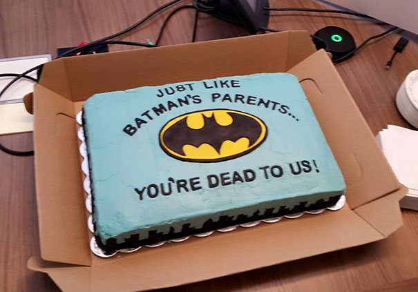 Farewell cake with Batman theme, humorous message: "Just like Batman's parents… You're dead to us," in office setting.