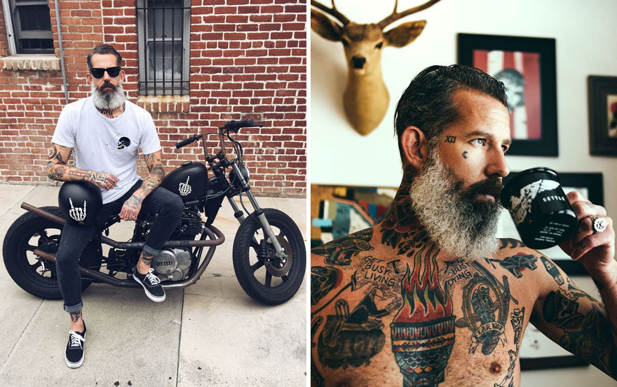 Tattooed older man with a beard sitting on a motorcycle and drinking coffee, redefining handsome style.