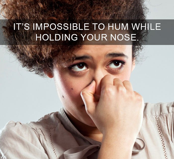 Person holding nose to show it’s impossible to hum, illustrating amazing facts that change the way you see the world.