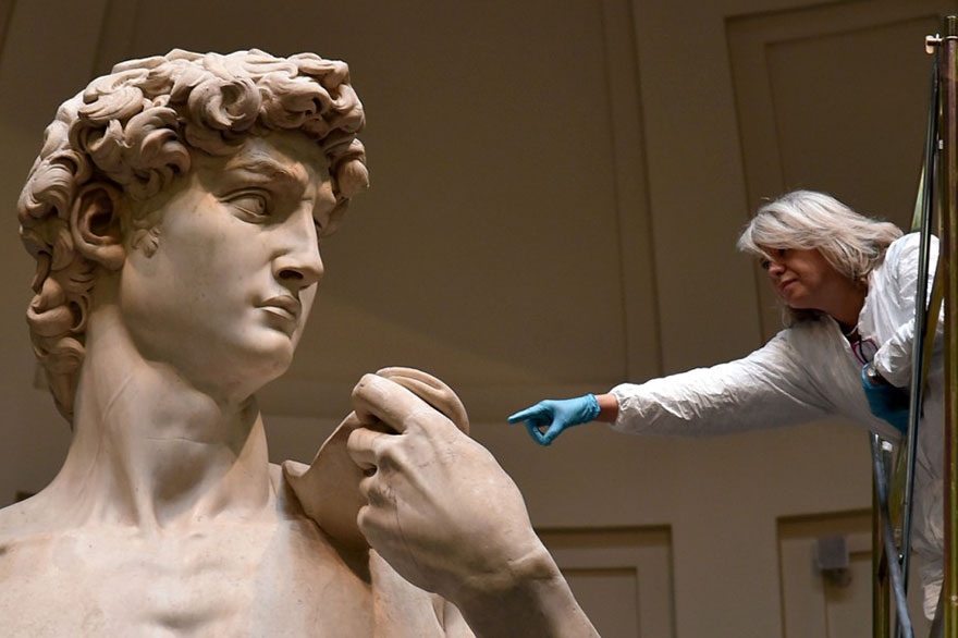 Photography of David Michelangelo statue to compare the size with the museum worker. Photography of David Michelangelo statue to compare the size with the museum worker.