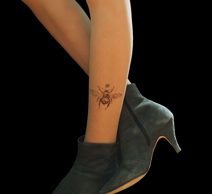 Tattoo tights with bee design, creating illusion of inked legs, paired with stylish heeled boots.