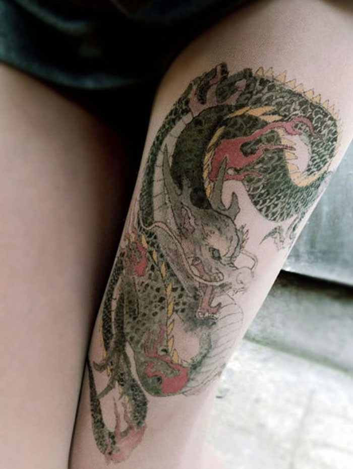 Tattoo tights with a dragon design creating an inked illusion on a person's leg.