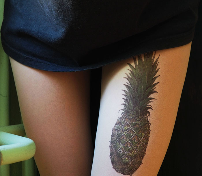 Tattoo tights with pineapple design creating illusion of inked leg under a black skirt.