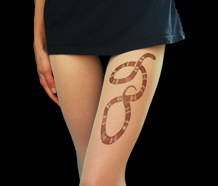 Tattoo tights featuring a snake design create an illusion of inked legs under a black skirt.