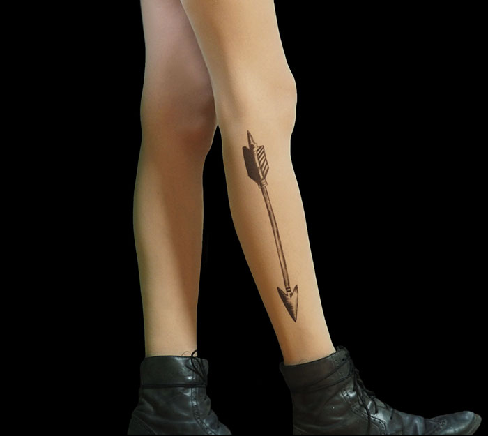 Tattoo tights with arrow design, creating an illusion of inked legs, paired with black boots.