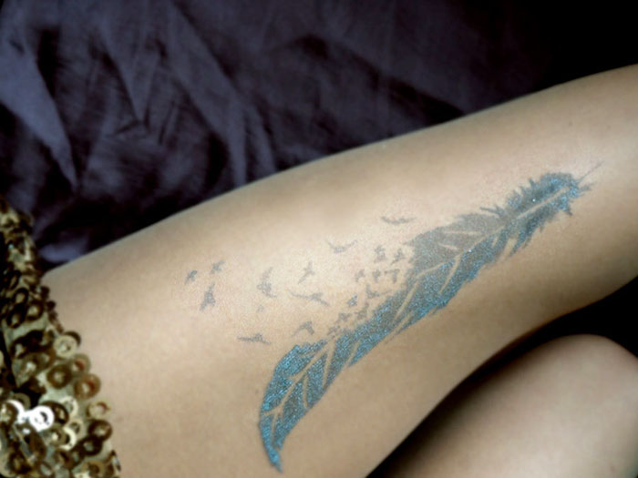 Tattoo tights with a feather design creating an inked illusion on a leg.