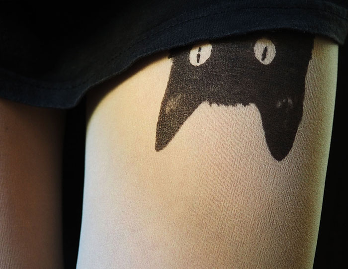 Tattoo tights with a playful black cat design, creating an illusion of inked legs under a black skirt.