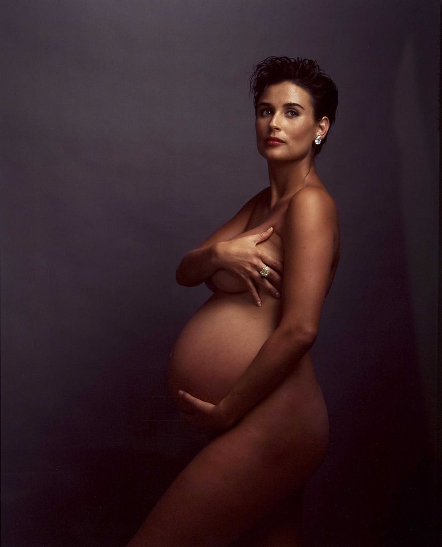 Pregnant woman posing in an iconic photograph with a dark backdrop.