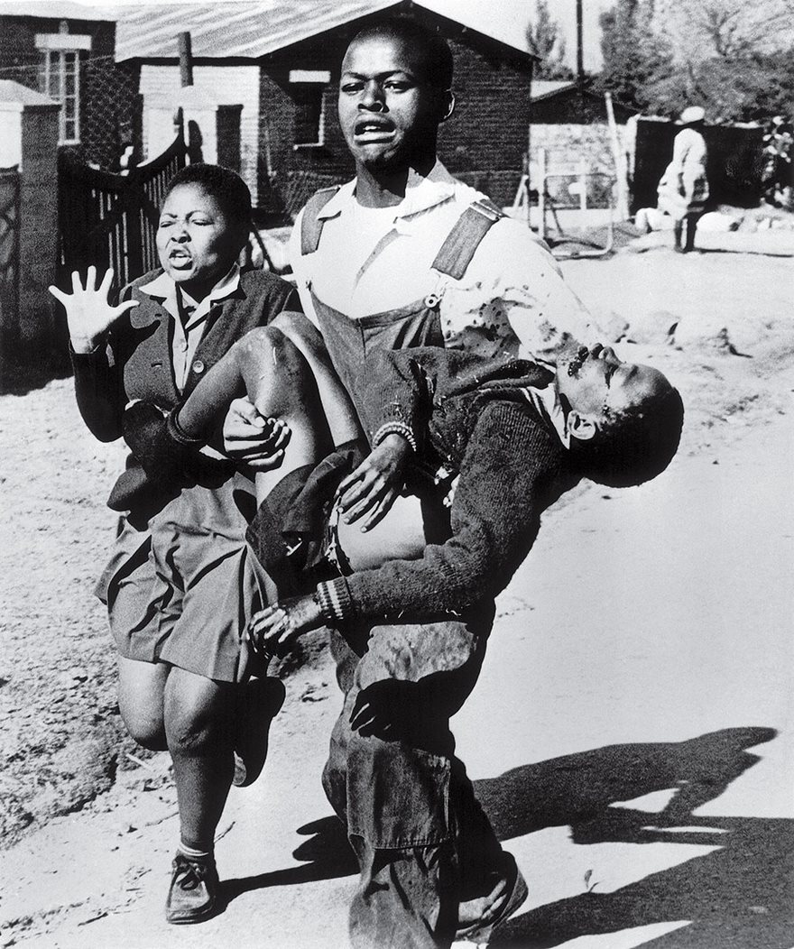 Historic photo of a young man carrying a child, symbolizing struggle and courage, with a distressed woman beside them.