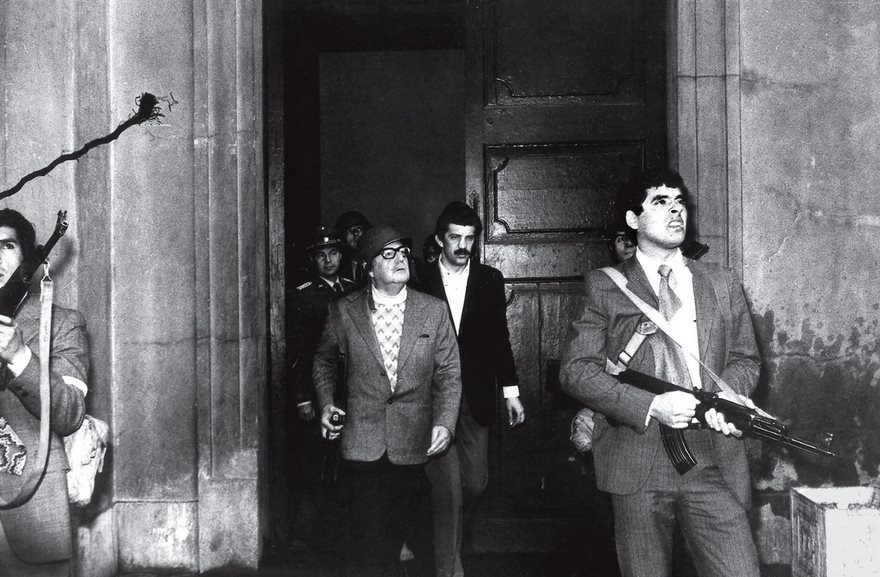 A historic photo featuring armed men exiting a building, capturing a tense moment in history.