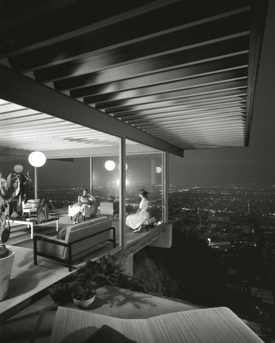 Modern home with a glass wall offers a panoramic city view at night, featured in famous historical photos.