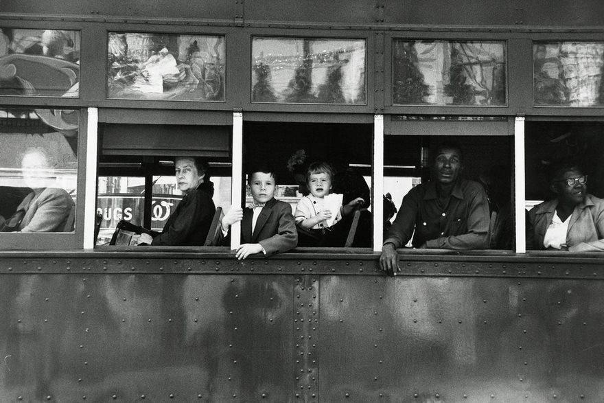 People of diverse backgrounds sitting inside a historic bus, looking out from the windows, capturing an iconic moment.