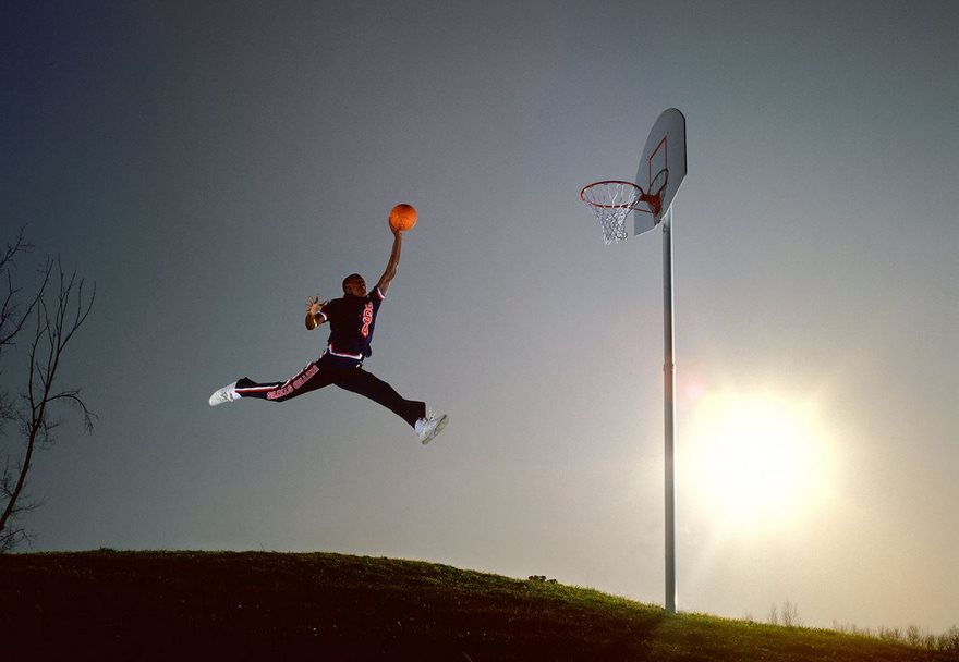 A basketball player mid-air, slam dunking against a bright sky, capturing a famous moment in sports history.