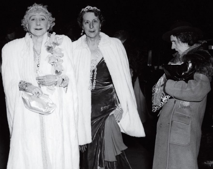 Two elegantly dressed women in white coats at an event, representing one of the most famous photos in history.