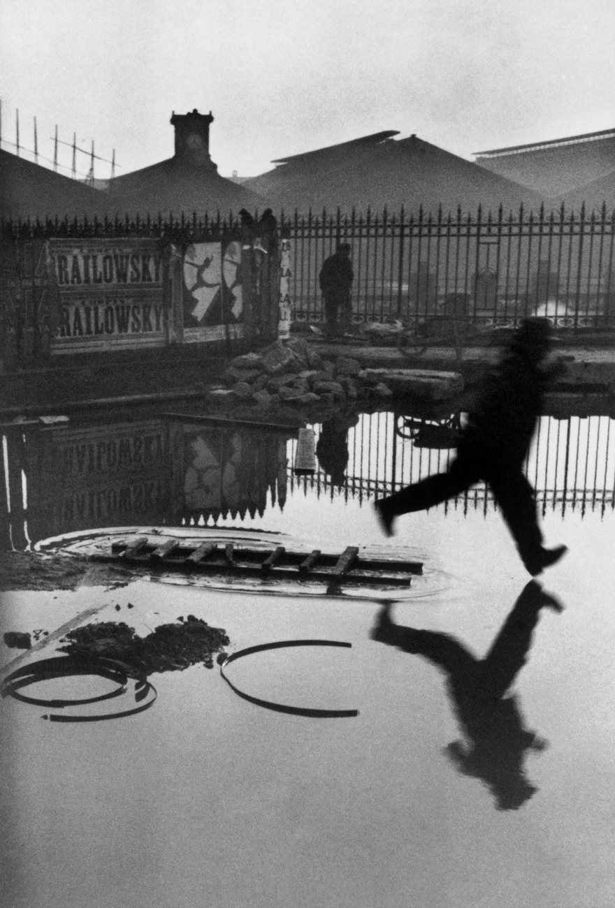 A man in motion mid-air, running across a puddle, capturing a famous historical moment in photography.