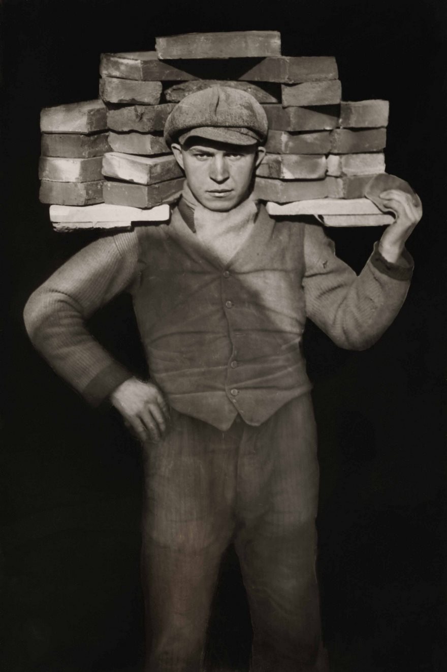 Man carrying bricks on shoulders, iconic historical photograph.