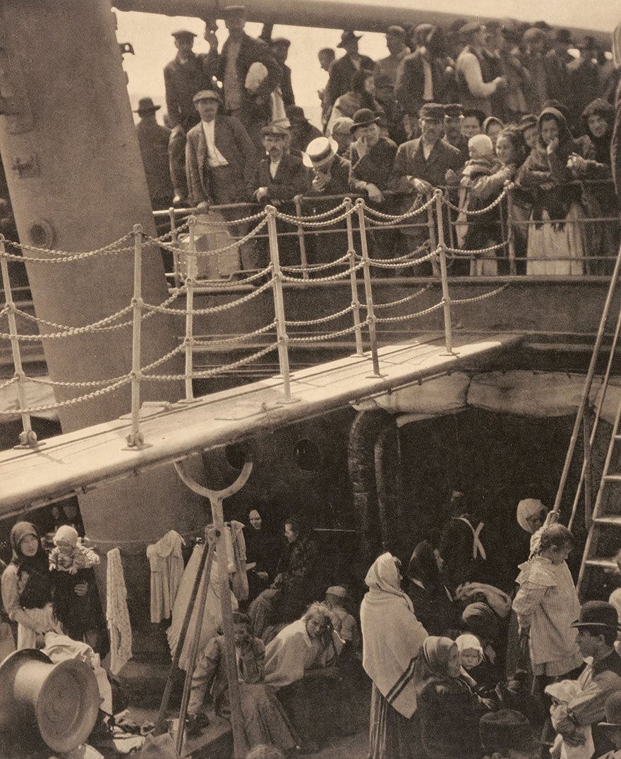 Historic photo of immigrants on a ship's deck, showcasing early 20th-century migration.